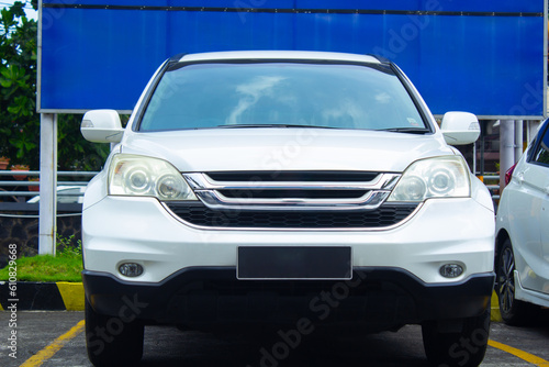 front view of white suv or crossover car in showroom car park with rusty chain barrier