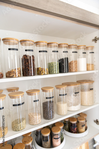 Neatly organized labeled food pantry in a home kitchen with spices grains flour rice sugar nuts