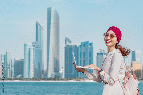 Young woman working on her laptop on the beach, driven by the energy and vitality of the Abu Dhabi skyline, United Arab Emirates capital