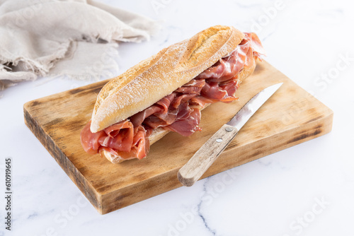 Spanish serrano ham sandwich on white marble background