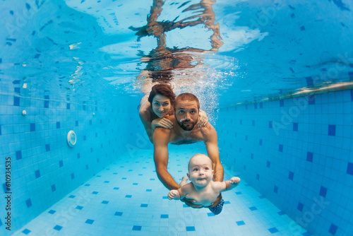 Happy family - mother, father with baby boy swimming, diving underwater with fun in blue pool. Healthy lifestyle, active parents, people water sports activity on summer vacation with child