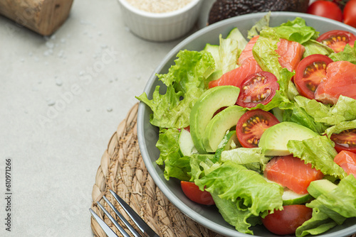 Vegetable salad with fish, tomatoes, avocado and cucumber on a gray background