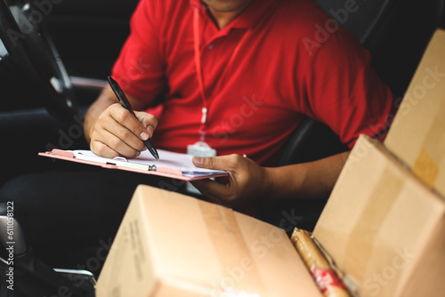 Hand of delivery man checking shipment documents while sitting in driver seat of van. Business cargo express and delivery service concept