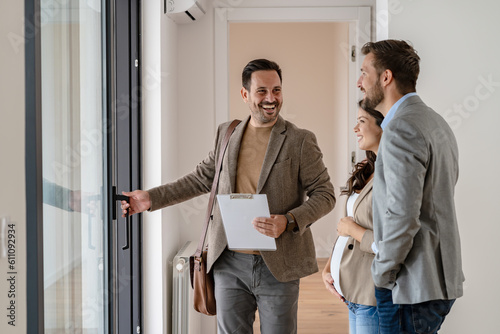 A young couple with a real-estate agent visiting an apartment for sale or for rent. Married couple buying an apartment. Real estate concept.