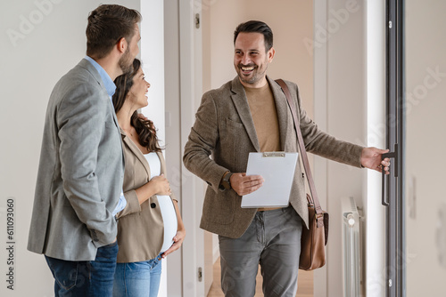 A young couple with a real-estate agent visiting an apartment for sale or for rent. Married couple buying an apartment. Real estate concept.