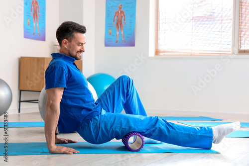 Male physiotherapist training with foam roller in rehabilitation center