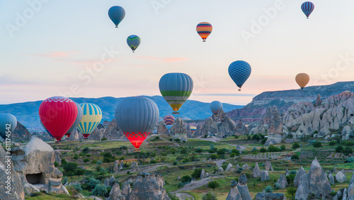 Cappadocia Turkey. Hot air balloons flying over fairy chimneys at sunrise in Cappadocia. Travel to Turkey. Touristic landmarks of Turkiye. Selective focus included.