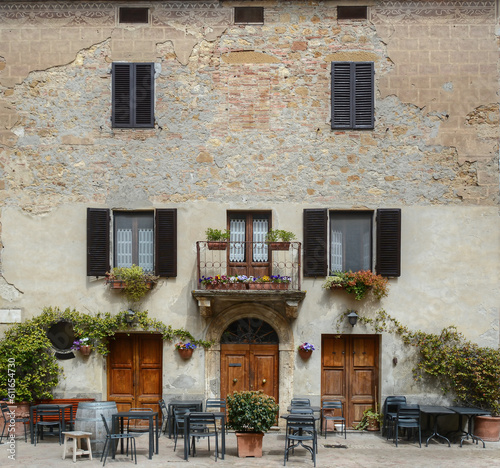 A frontal photo of a facade of an stone hose in Italy with a closed restaurant on the ground floor 