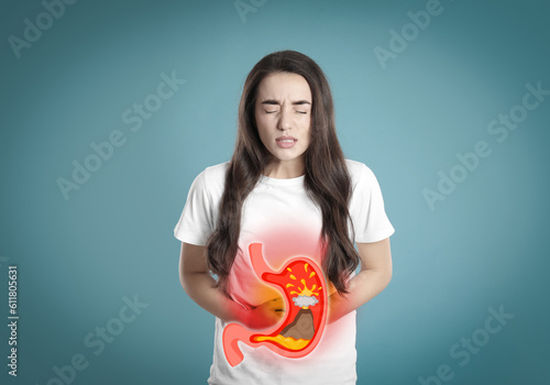 Woman suffering from heartburn on turquoise background. Stomach with erupting volcano symbolizing acid indigestion, illustration