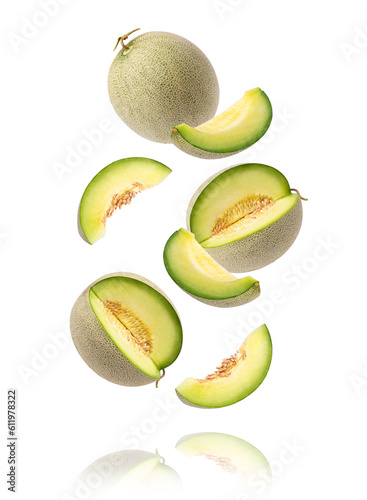 Green cantaloupe melon with cut slice flying in the air isolated on white background.