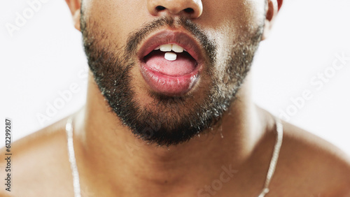 Man, mouth and hands with pill, drug or medication for relief, healthcare or substance abuse against a white studio background. Lips and tongue of male addict taking medical supplement vitamin tablet