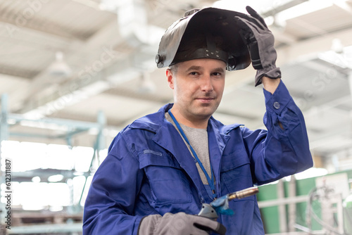 Portrait confident welder with welding torch in factory