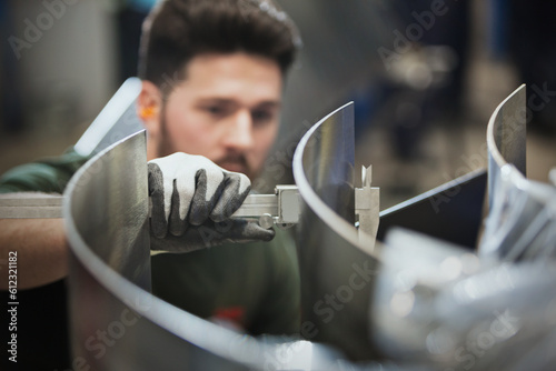 Worker measuring steel with calipers in steel factory