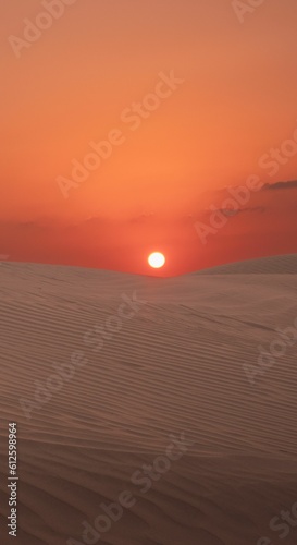 Vertical shot of the orange sunset sun shining over dry sand dunes