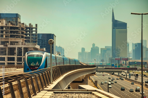 Train on monorail of Dubai modern subway at urban skyscrapers background. Wallpaper of city metropolitan metro in business district desert arabic emirate. Public transport concept. Copy ad text space