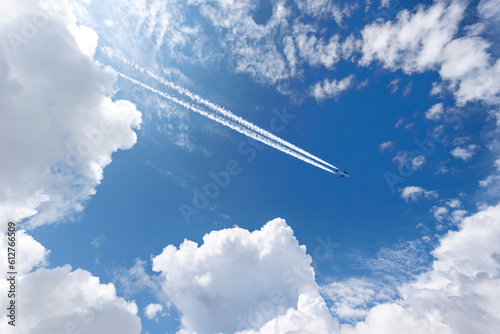 Airliner with contrails flying in a clear blue sky with beautiful cumulus clouds or cumulonimbus. Photography, Full frame.