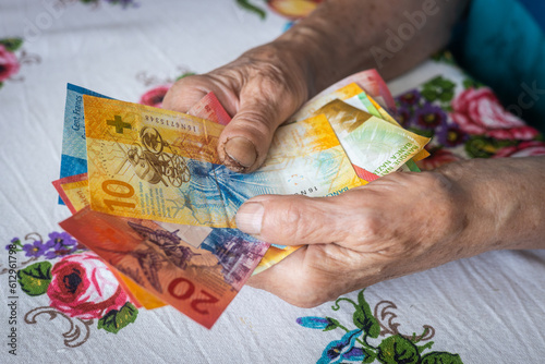 pensioner holds a bunch of low denomination banknotes in her hands, Cost of living for a senior citizen in Switzerland, Pensions and the Swiss social system for the elderly