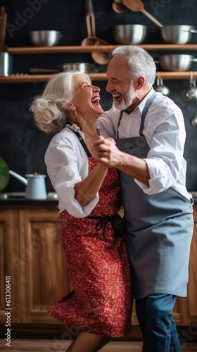 loving senior couple, grey-haired man and woman, while they dance, laugh, and prepare home kitchen