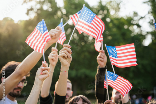 Group of people holds flags of the United States of America USA in the air celebrating citizenship at sunset outdoor - Copy space