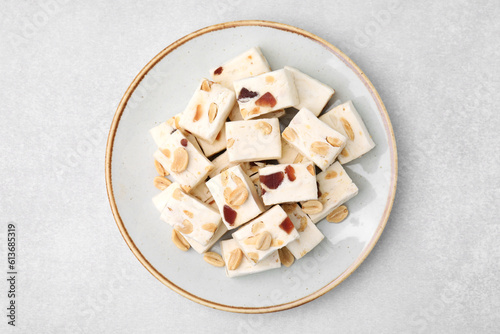 Pieces of delicious nutty nougat on light gray table, top view