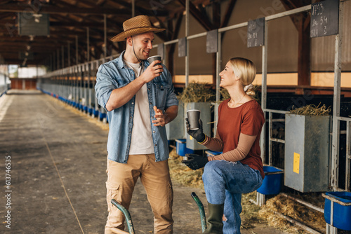 Male and female farmer having a coffee break during working hours in a stable.