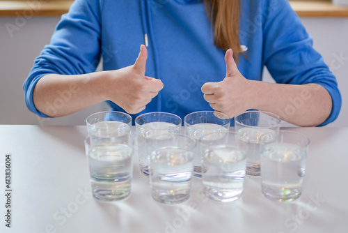 8 szklanek z wodą i kobieta podnosząca kciuki w górę 