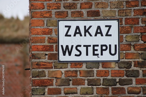 No trespassing sign (In Polish "ZAKAZ WSTĘPU") on red brick wall, Poland