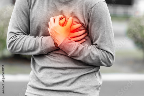 Man covering his heart painfully outdoors, concept of sudden heart attack. 