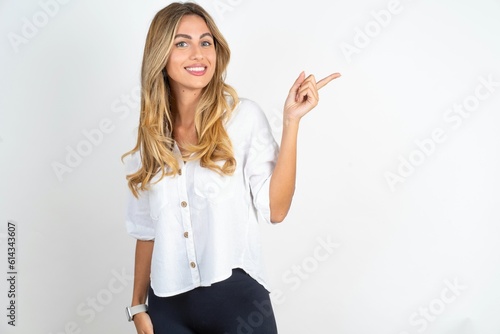 Young caucasian business woman wearing white shirt over white background looking at camera indicating finger empty space sales