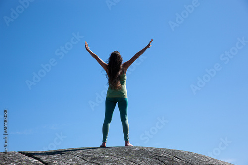 Frau mit ausgestrckten armen isoliert auf einem Berggipfel bei blauem Himmel
