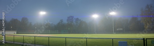 WIDE view of empty baseball field at dusk under heavy rain. Stadium flood lights are turned on. Shot with 2x anamorphic lens