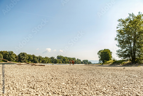 Portrait of a young woman and her horse at a gravel beach bank of river danube; Female equestrian summer with her bay brown andalusian x arab gelding