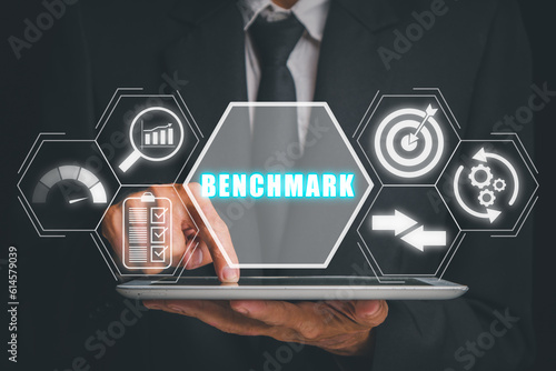 Benchmarking concept, Businessman hand touching on tablet computer with benchmarking icon on virtual screen.