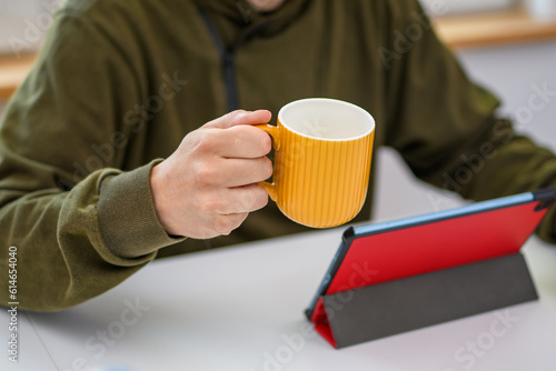 Mężczyzna przeglądający poranne wiadomości na komputerze popijający kawę z kubka