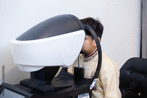 Indian child boy examining eyesight modern ophthalmology equipment in clinic. Patient kid male scan checkup iris examines ophthalmological hospital.