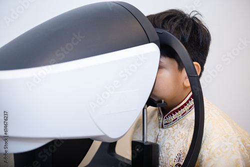 Indian child boy examining eyesight modern ophthalmology equipment in clinic. Patient kid male scan checkup iris examines ophthalmological hospital.
