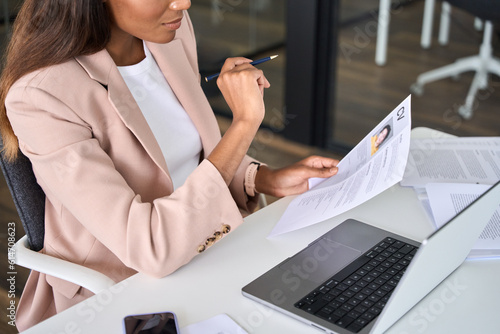 Close up view of female HR manager reading cv during virtual remote online job interview concept. Business woman employer holding resume hiring recruit in professional recruitment agency.