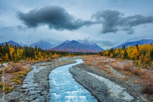 Landscape with mountains, boreal forest in autumn colors and river in the blue hour before sunrise, Yukon territory, Canada