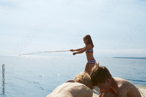 Girl in bikini fishing off sunny dock