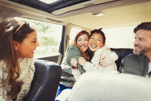 Enthusiastic female friends hugging in back seat of car