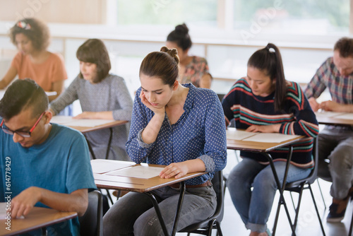 College students taking test at desks in classroom