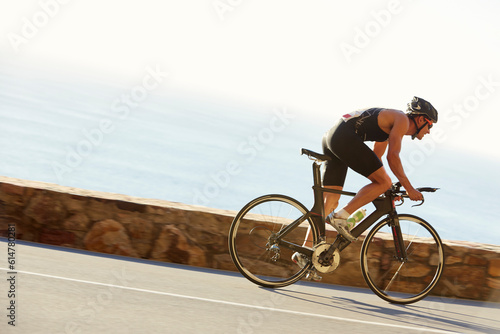 Male triathlete cyclist racing on ocean road