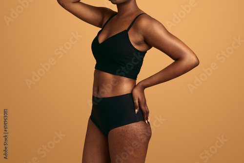 Crop black woman with stretch marks touching waist
