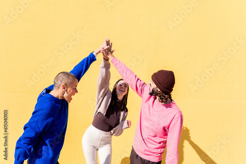 joyful young people high fives and having fun together on yellow background, concept of friendship and happiness, copy space for text