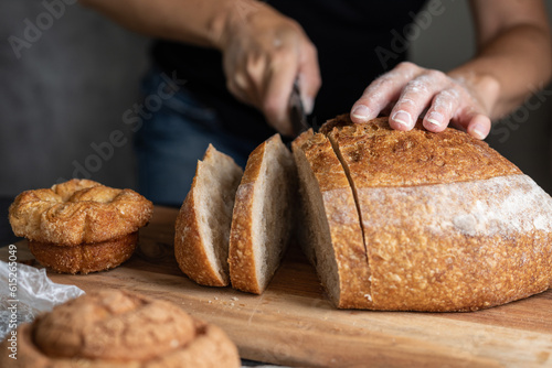 person cutting a loaf of bread on the table, space for text, focus on the bread