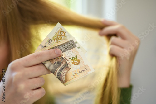 Usługi fryzjerskie, polski banknot 200 pln trzymany na tle pasma włosów 