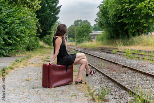 Femme attendant le train assise sur une valise