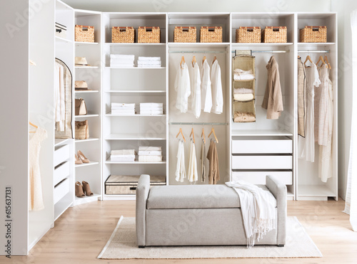 A cozy bedroom with white walls and a closet, featuring clothes hung up in neat fashion