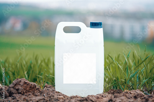 white plastic container with agricultural chemicals or fertilizers on a green field