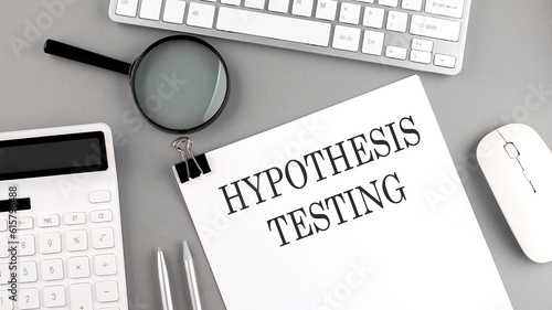 Hypothesis testing written on paper with office tools and keyboard on the grey background